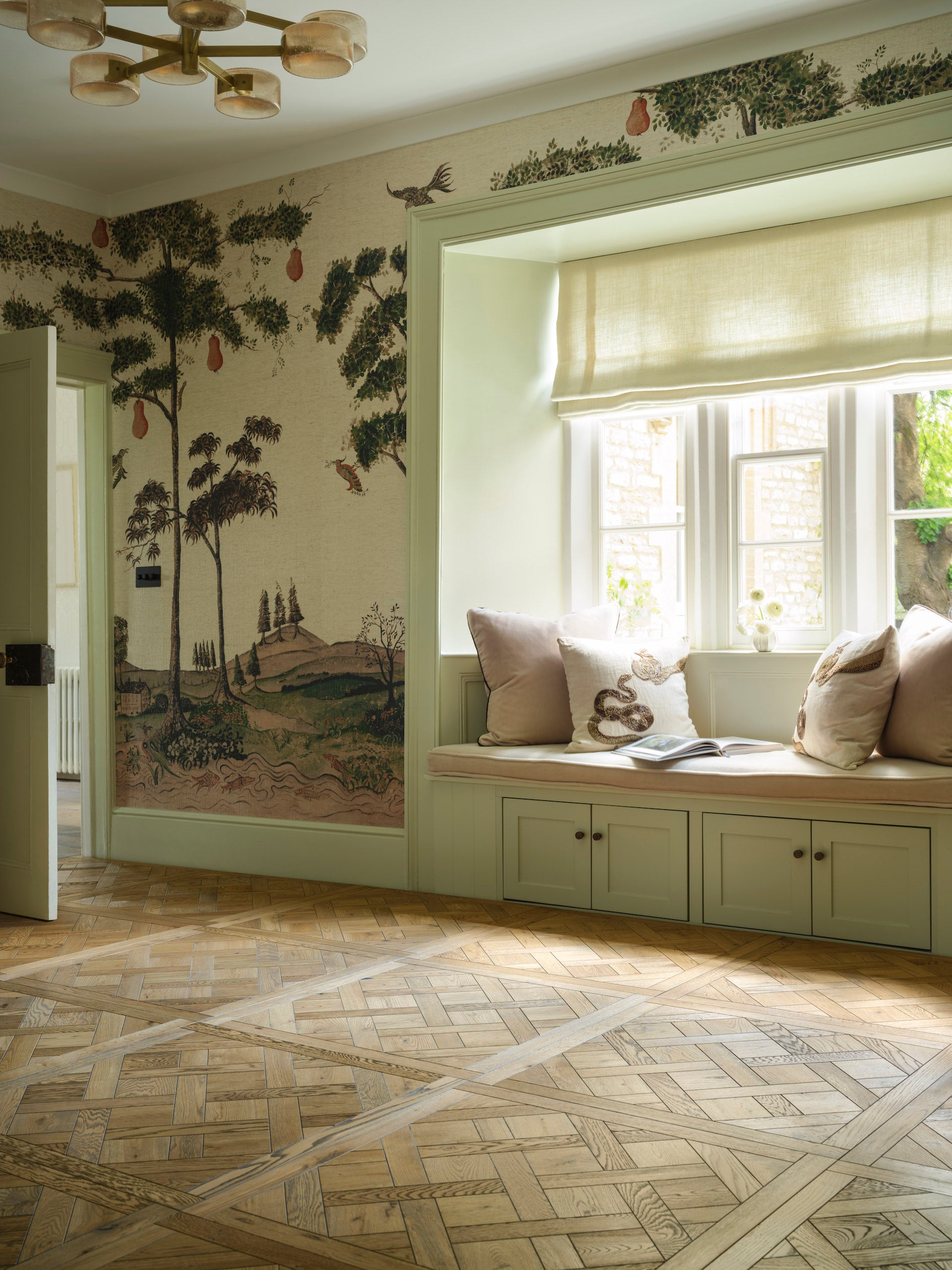 Living room with decorative wall mural, window seat, and parquet floor.